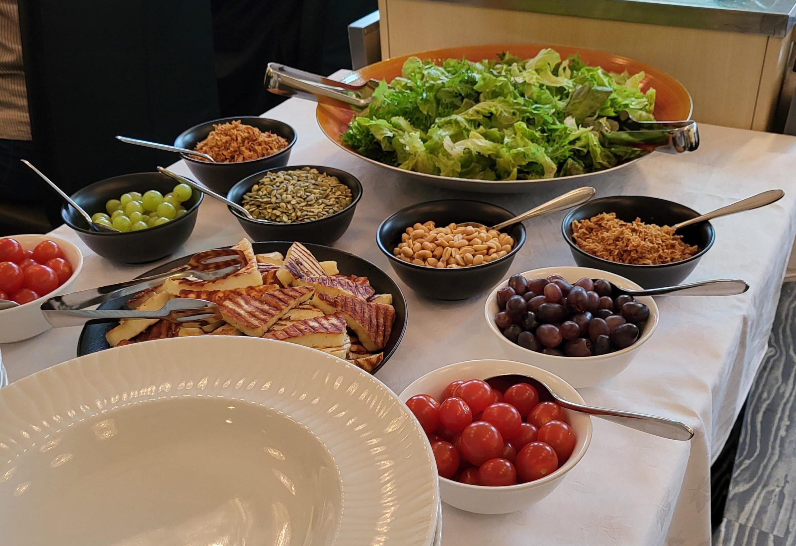 Valkeakosken ammattiopisto, VAAO, pöydällä koottavan salaattilounaan raaka-aineet kulhoissa, vihanneksia, hedelmiä, pähkinöitä, halloumia.