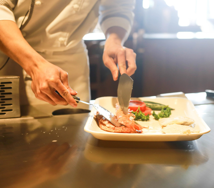 Valkeakosken ammattiopisto, VAAO. Kuvassa näkyy kokin kädet ja hän asettelee ruokaa lautaselle.