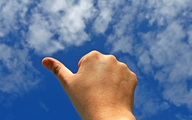 Valkeakosken ammattiopisto, VAAO. Kuvassa käsi, joka näyttää peukkua sinistä taivasta vasten. Taivaalla vähän valkoisia pilviä.