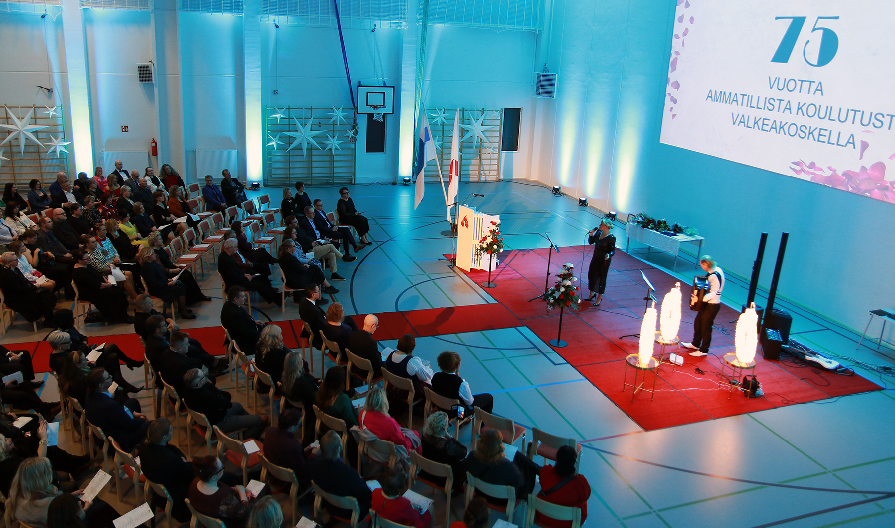 VAAO, Valkeakosken ammattiopisto, Juhlatilaisuus, laulaja laulaa yleisön edessä, haitaristi säestää. Kuva Marika Renfors