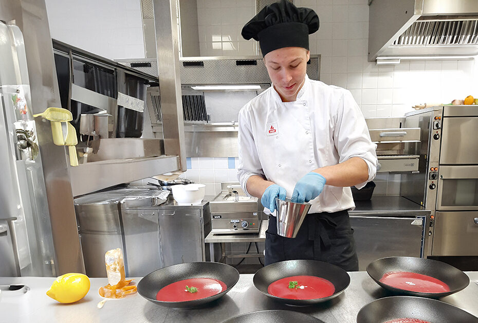 Valkeakosken ammattiopisto, VAAO. Kokkiopiskelija valmistaa tarjoilua varten keittoannoksia.
