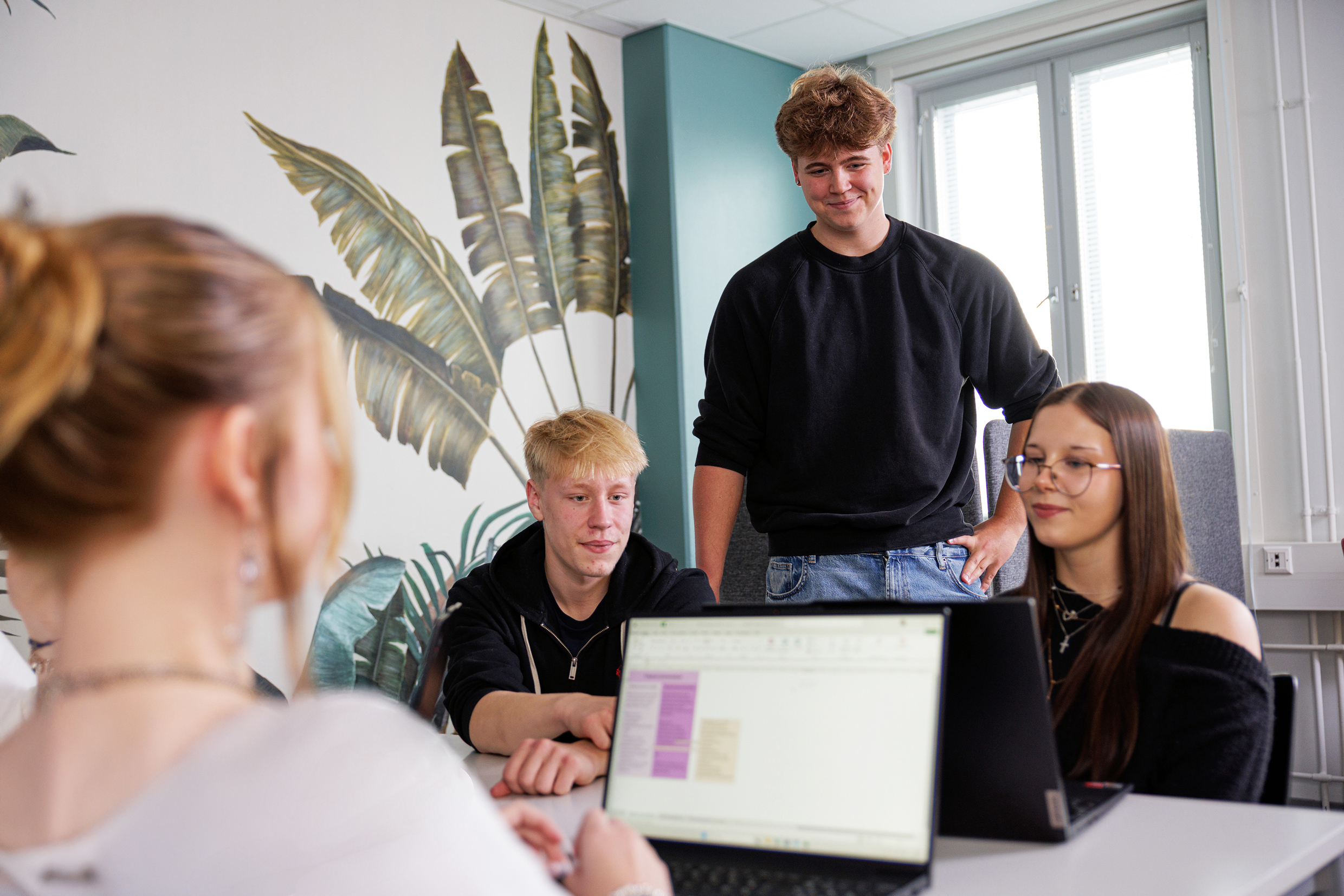 Opiskelijat VAAOssa opiskelemassa liiketoimintaa. Opiskelijat istuvat, yksi mies seisoo!