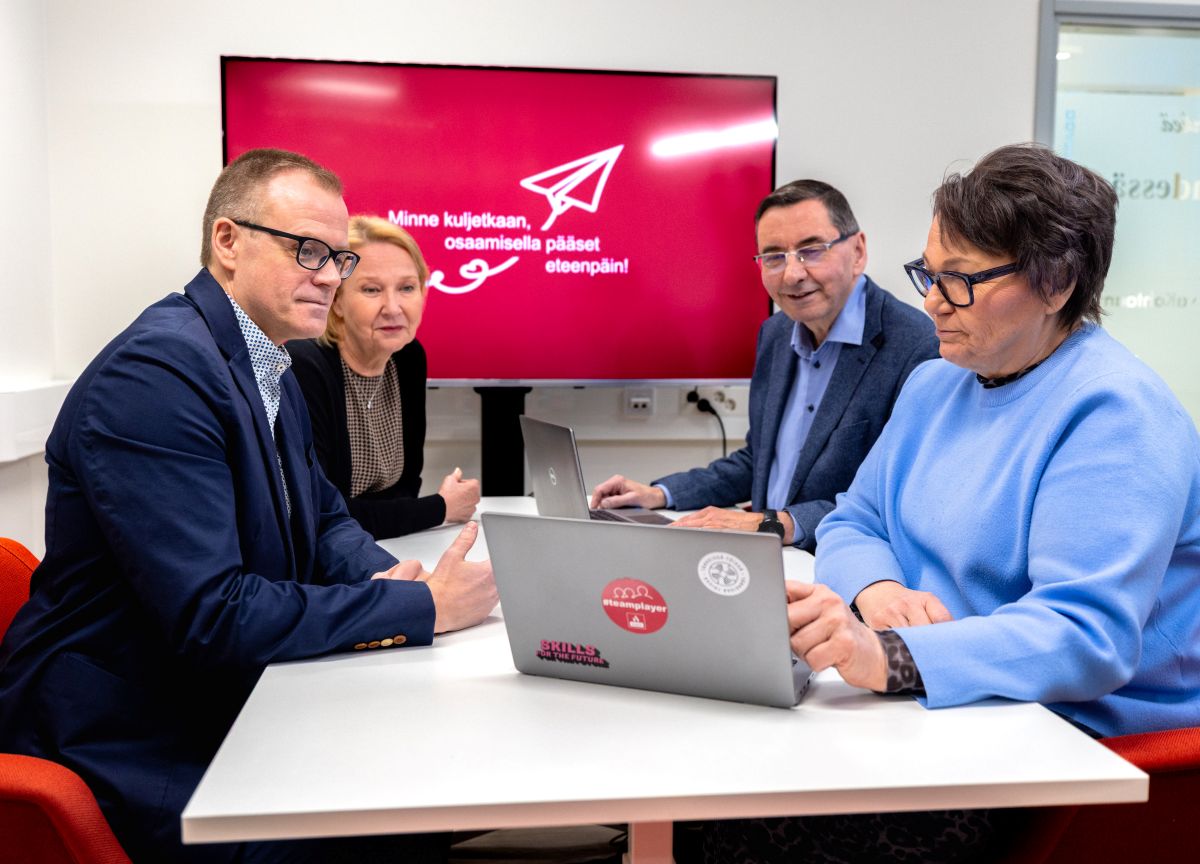 VAAOn johtotiimin jäsenet istuvat kokouspöydän ääressä ja katsovat yhdessä jotain kannettavalta tietokoneelta.