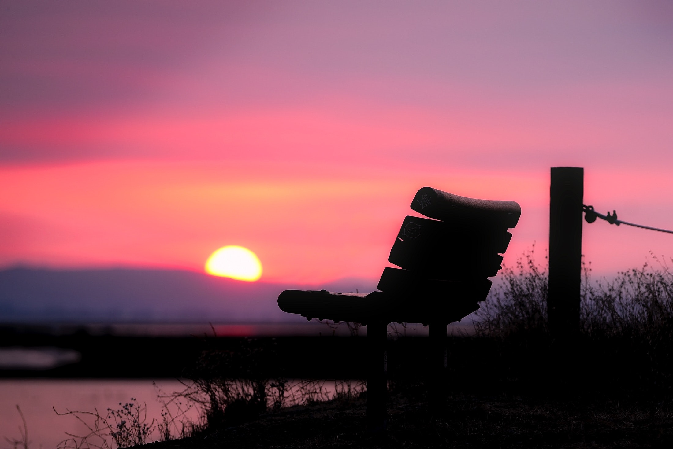 Valkeakosken ammattiopisto, VAAO. Kuvituskuvassa on penkki jossa ei istu kukaan ja taustalla näkyy auringonlasku.